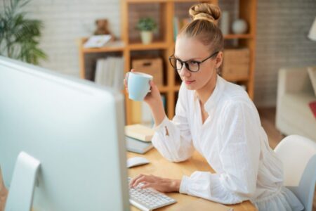 mulher em frente ao computador com uma xícara na mão