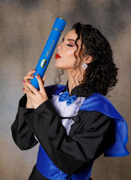 mulher com beca de formatura segurando diploma