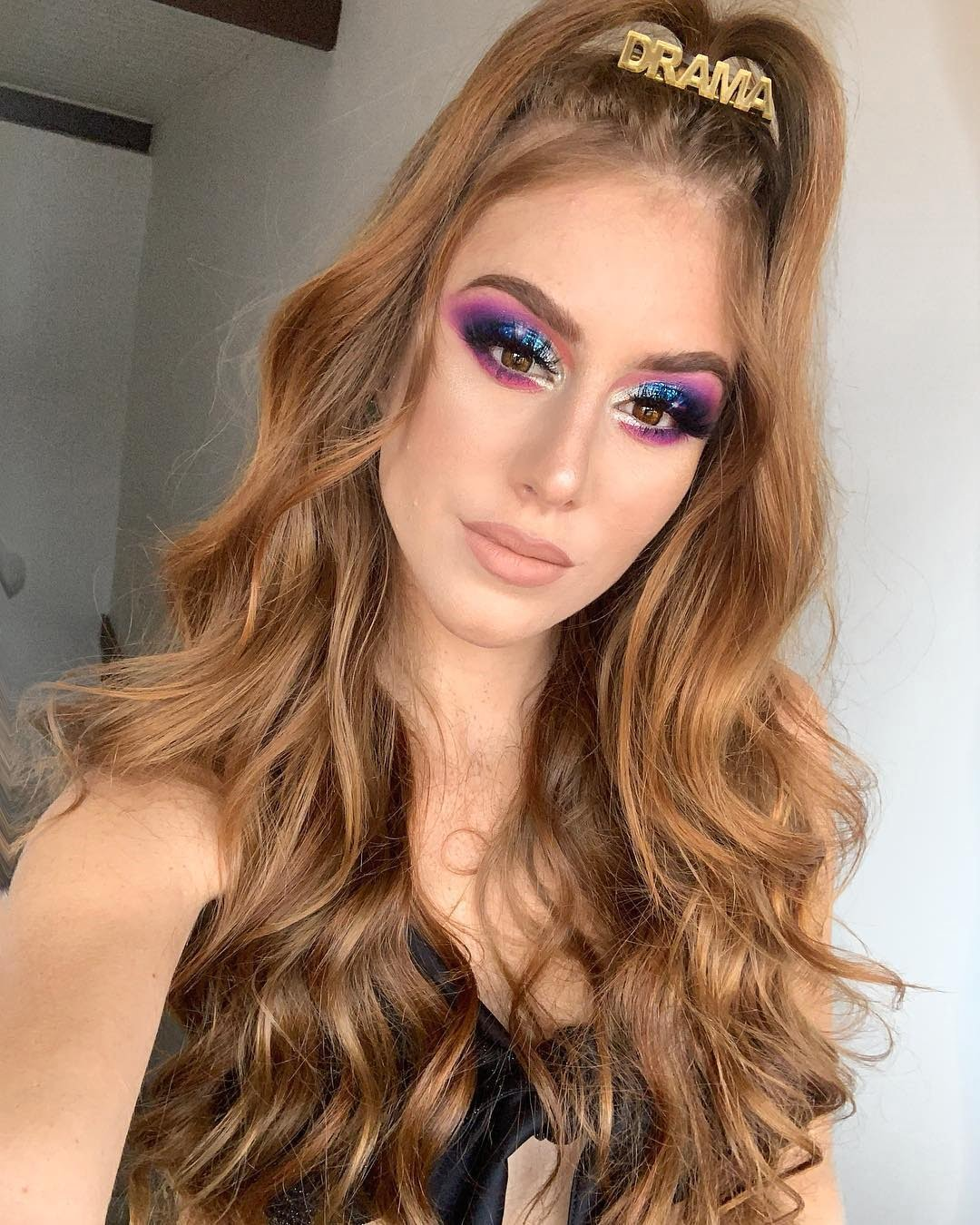 mulher usando cabelo semi preso em um coquinho alto e make colorida
