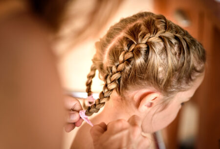 mulher fazendo penteado em menina