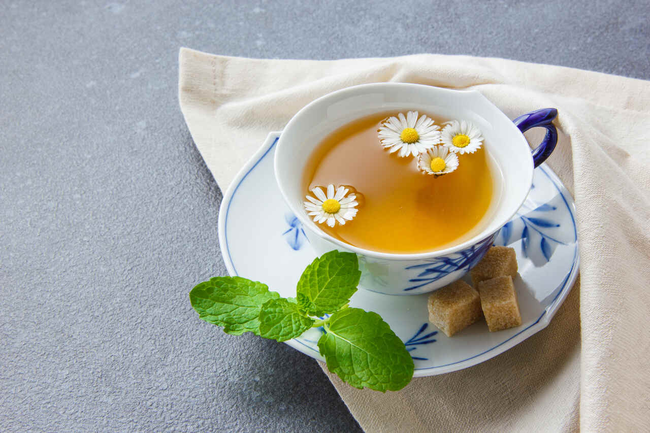 Chá para colorir cabelo sem tinta Xícara de chá de camomila com flores enfeitando