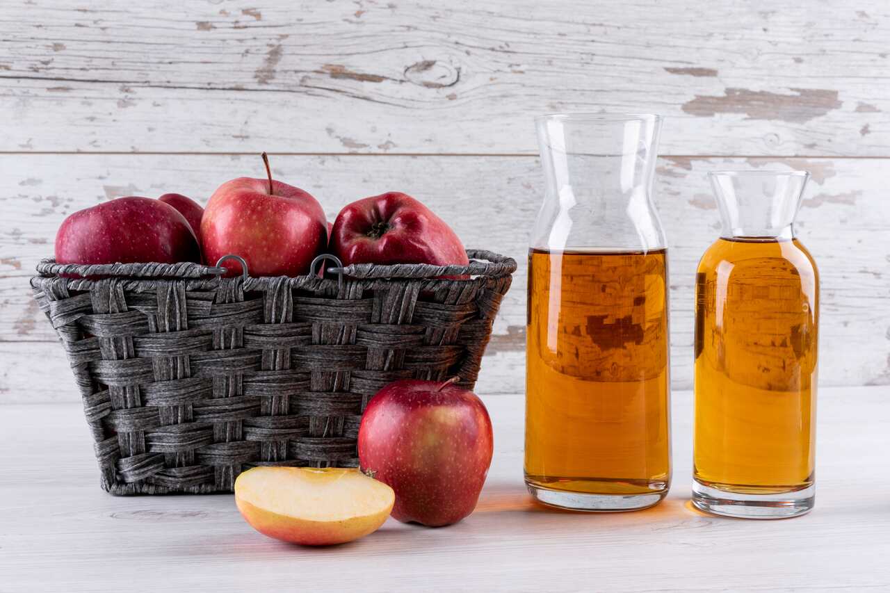 Clareador de Cabelo 2024 Mesa com uma cesto de maças e garrafas com vinagre da fruta