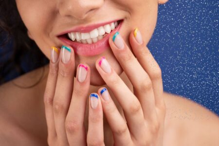 Francesinha unhas decoradas carnaval: ideias coloridas para a folia Mulher sorrindo com francesinha unhas decoradas carnaval em cores vibrantes, com base nude e pontas coloridas em estilo moderno e festivo.