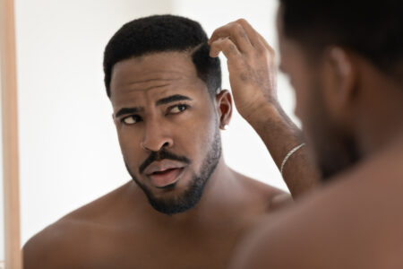 Pomada efeito matte: como usar no cabelo masculino para um visual moderno homem aplicando pomada efeito matte no cabelo masculino em frente ao espelho para modelar o penteado