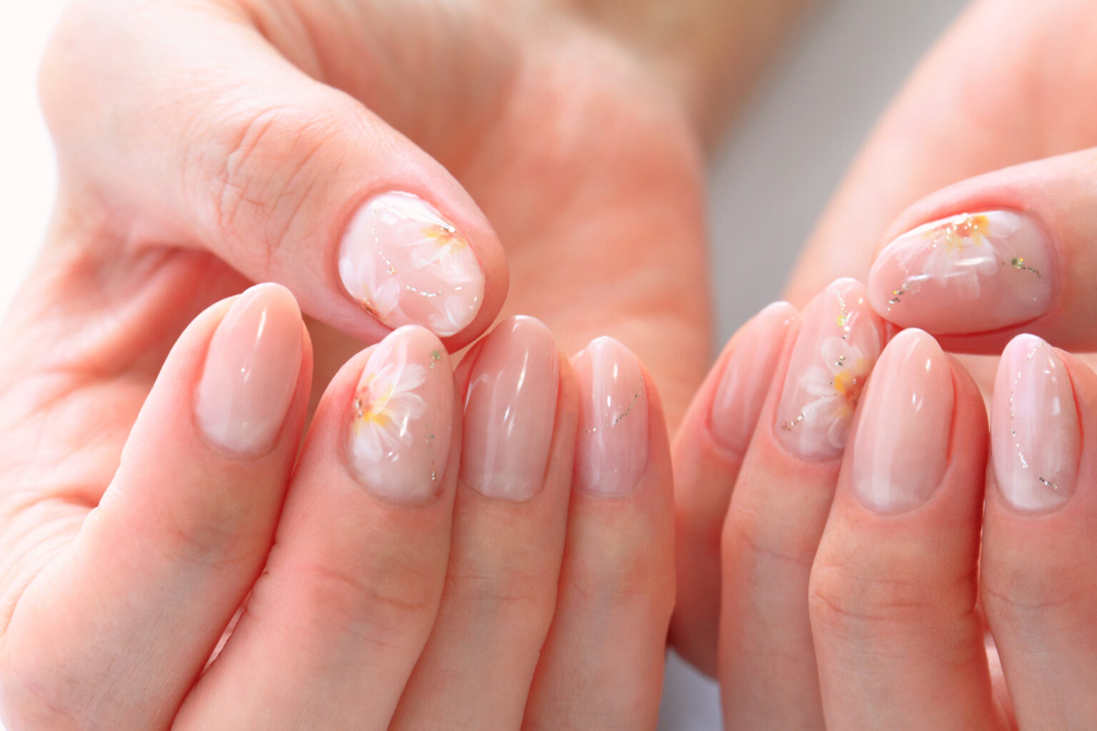 Unhas com esmalte em gel decoradas com flores delicadas e acabamento brilhante.