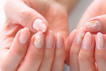 Esmalte em gel: guia completo com tudo o que você precisa saber Unhas com esmalte em gel decoradas com flores delicadas e acabamento brilhante.